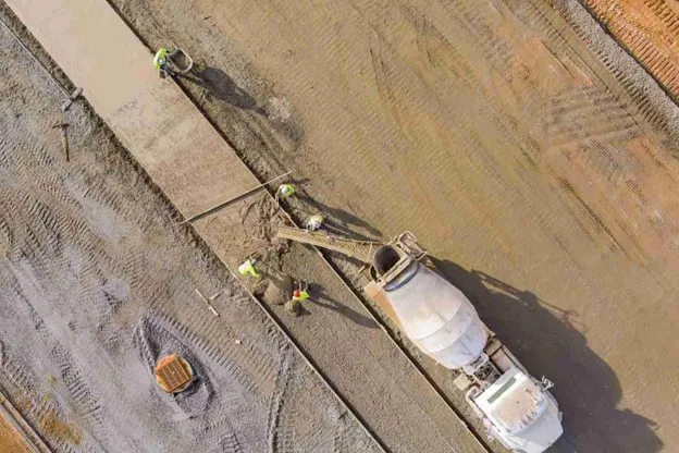 Construction worker preparing concrete foundation with rebar in hot Texas weather conditions
